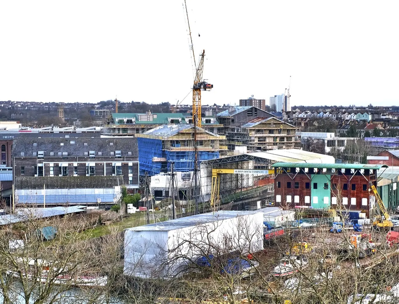 A riverside town-centre building site, with a tower crane over new housing blocks in scaffolding
