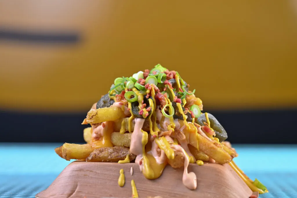 Loaded fries with cheese sauce, mustard, pickles and spring onion