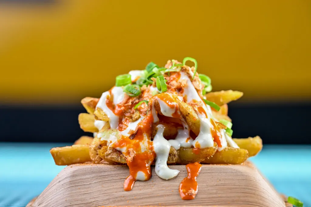 Fries with hot sauce, white sauce and spring onion