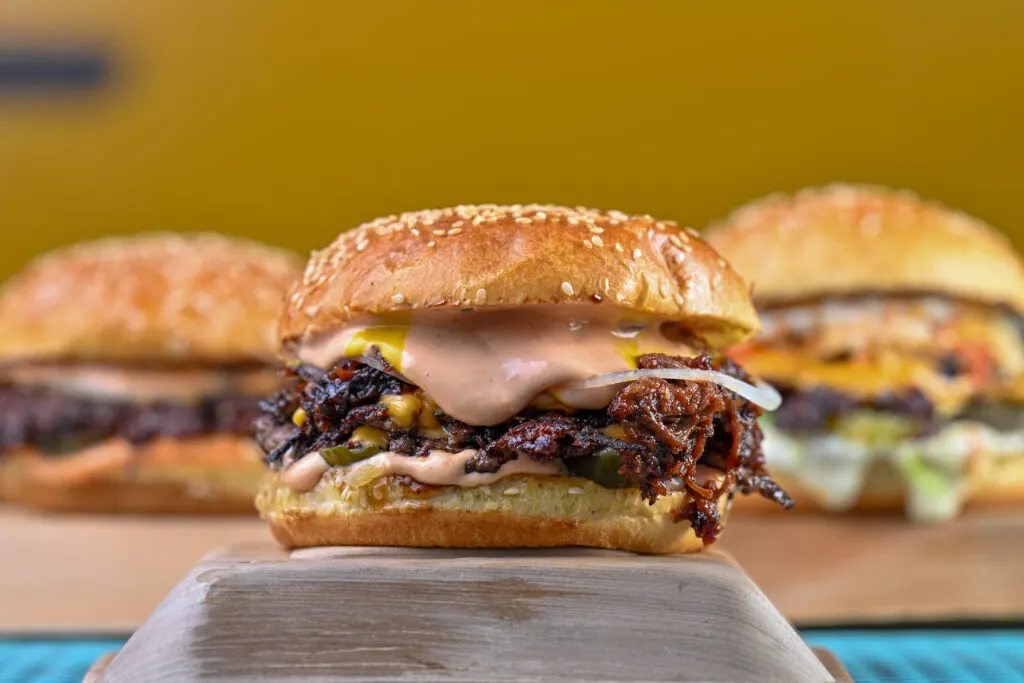 Smash burger with crispy onions and pink sauce, two more burgers behind